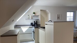 Een moderne keuken met witte kastjes, een inbouwfornuis en een koffiezetapparaat.