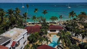 A resort with a pool, palm trees, and a view of the ocean with boats. - Solaz Boutique Hotel (Las Terrenas)
