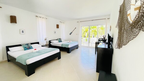 A hotel room with two beds, a desk, and a large window with a view of greenery. - Solaz Boutique Hotel (Las Terrenas)