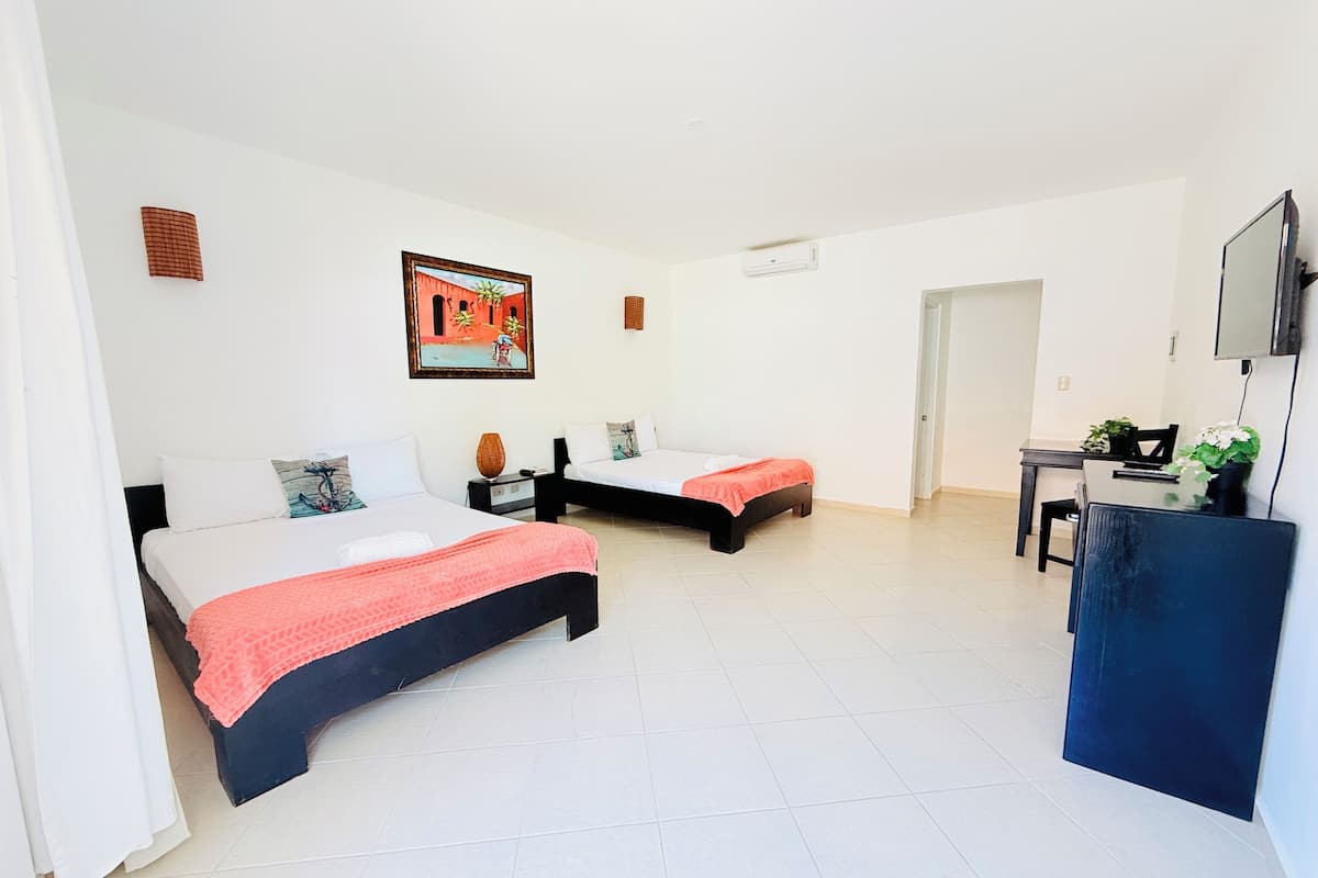 A hotel room with two beds, a desk, a chair, a television, and a painting on the wall.
