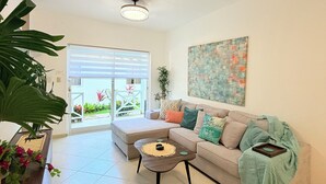 A living room with a sofa, a coffee table, a potted plant, and a painting on the wall. - Solaz Boutique Hotel (Las Terrenas)