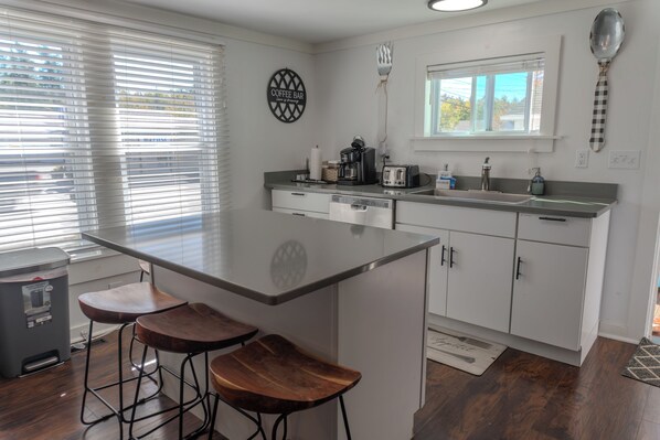 Una cocina moderna con una isla central, taburetes de bar, una cafetera y un tostador.