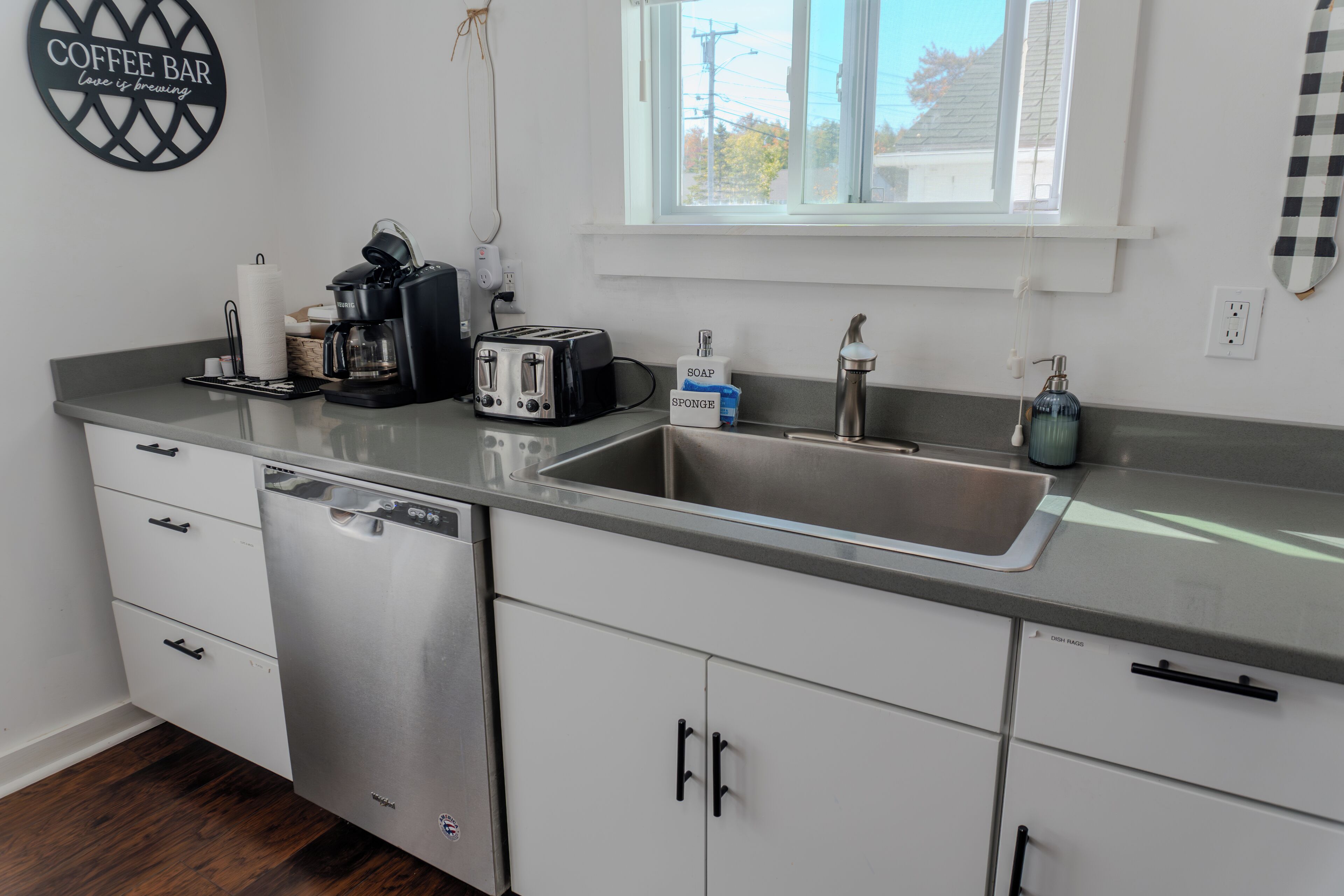 Cozinha moderna com cafeteira, torradeira e máquina de lavar louça.