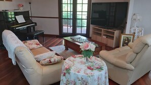 A living room with a piano, two sofas, a coffee table, and a television. - Beautiful room, a comfy king bed, includes a delicious continental breakfast. (Balingup)