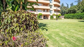 A multi-story building with balconies, a well-maintained lawn, and surrounding greenery.