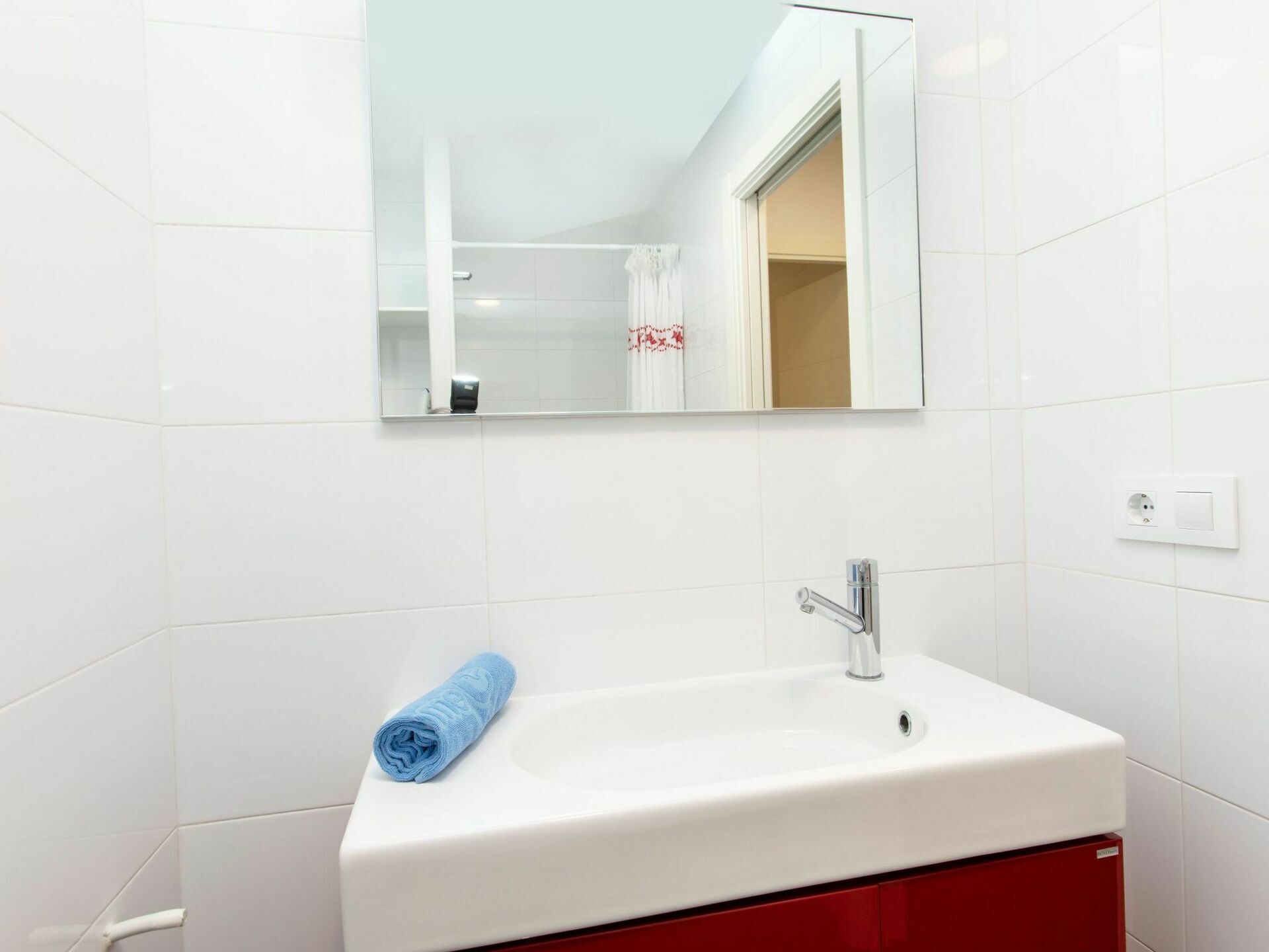 A bathroom with a white sink, a mirror, and a towel.