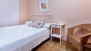 Ein Schlafzimmer mit einem Bett, einem Nachttisch, einem Sessel und einem Wandbild.