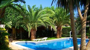 A swimming pool with a geometric tile pattern, surrounded by palm trees and lush greenery. - Beautiful private villa for 14 people with private pool, WIFI, TV, patio and pets allowed (Miami Platja)