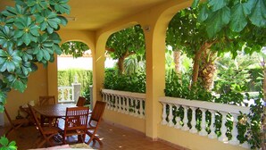 A covered patio with a round table and chairs, surrounded by arches and potted plants. - Beautiful private villa for 14 people with private pool, WIFI, TV, patio and pets allowed (Miami Platja)
