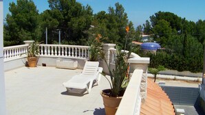 A rooftop terrace with white lounge chairs, potted plants, and a blue umbrella. - Wonderful private villa for 6 guests with private pool, A/C, WIFI, TV, patio and pets allowed (Miami Platja)
