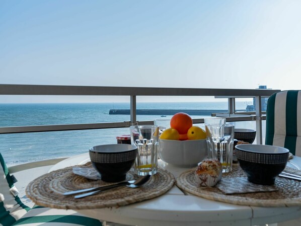 Enjoy a casual meal on the balcony with a scenic view of the water and distant pier.