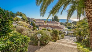 Un quartier résidentiel avec des maisons, un ciel dégagé et une vue sur la mer.