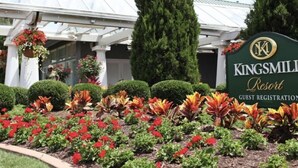 Skilt for Kingsmill Resort med et gæsteregistreringsområde, omgivet af velholdte blomsterbede og høje træer.