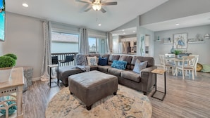 A spacious living room with a sectional sofa, ottoman, and a ceiling fan. - 2nd Floor, Shared Pool Hot Tub, Near Marina, Pickleball courts (Port Aransas)