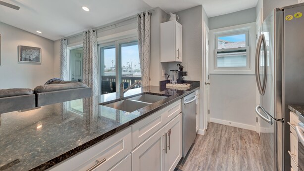 A modern kitchen with a granite countertop, white cabinetry, and a stainless steel refrigerator. - 2nd Floor, Shared Pool Hot Tub, Near Marina, Pickleball courts (Port Aransas)