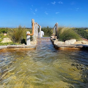 A clear water channel with wooden structures on either side, leading to a distant view. - Cozy Home | Seaside Retreat in Rye (Rye)