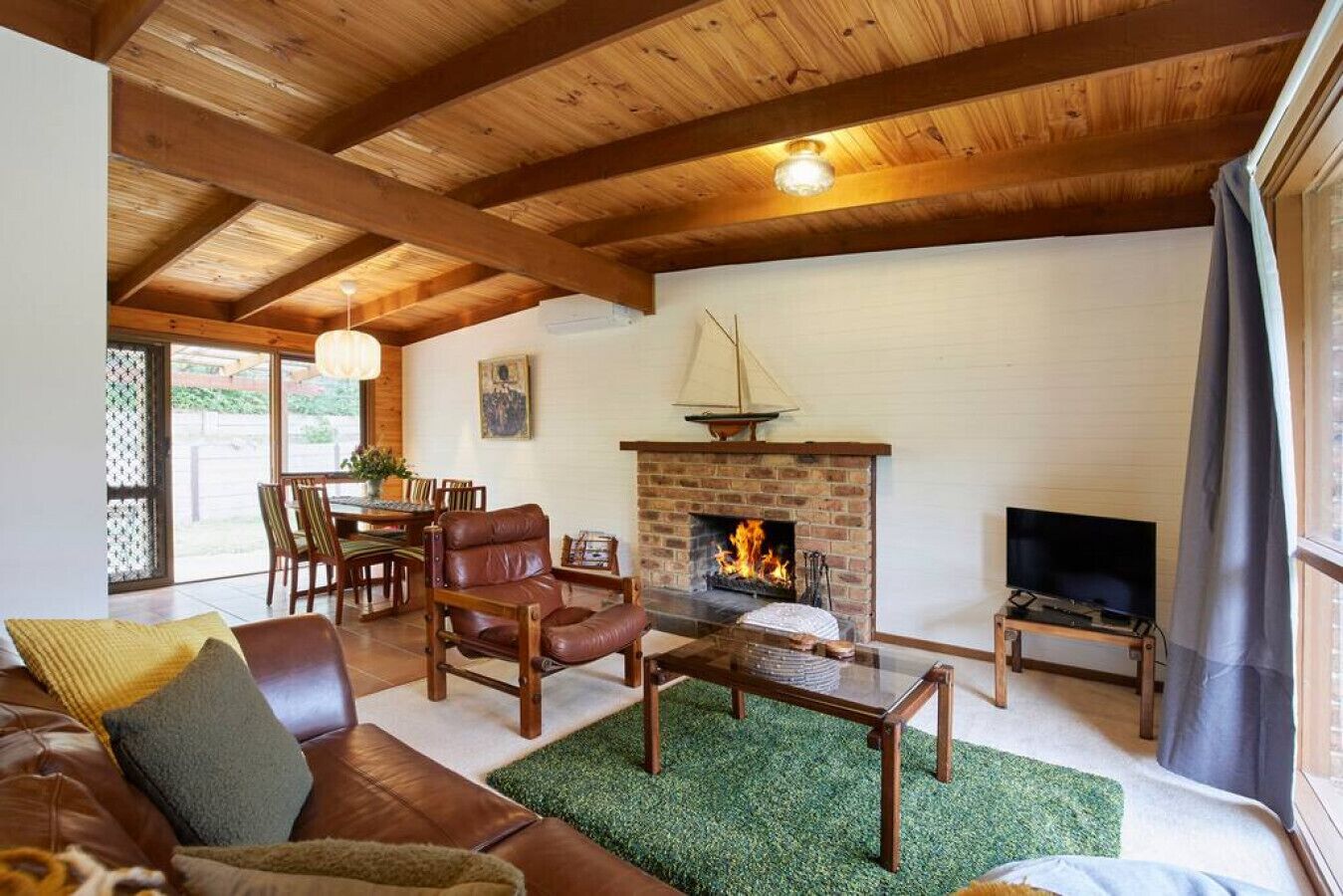 A cozy living room with a fireplace, leather furniture, and a TV.