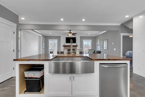 Een moderne keuken met een centraal eiland, een roestvrijstalen spoelbak en een geïntegreerde vaatwasser.