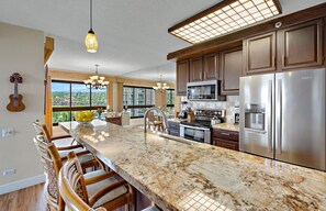 A modern kitchen with a large island, stainless steel appliances, and a view of the city.