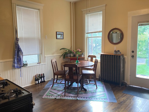 A dining area with a round table, chairs, a potted plant, and a radiator.