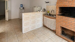 Una cocina con horno de ladrillo, refrigerador, dispensador de agua y piso de baldosas.