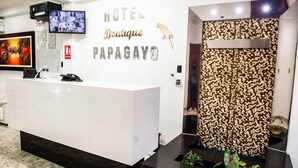 Un mostrador de recepción de hotel con diseño moderno, un televisor montado y una pared decorativa con textura de guijarros.
