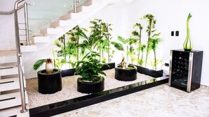 Un interior moderno con una escalera, macetas negras con plantas verdes y un enfriador de vino.