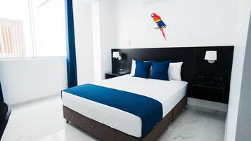 Een hotelkamer met een groot bed, een nachtkastje, een wandlamp en een decoratieve papegaai.