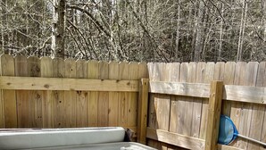 Ein Whirlpool mit einer Holzterrasse und einem Holzzaun im Hintergrund.