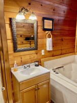 Un bagno con rivestimento in legno, dotato di lavandino, specchio e vasca da bagno.