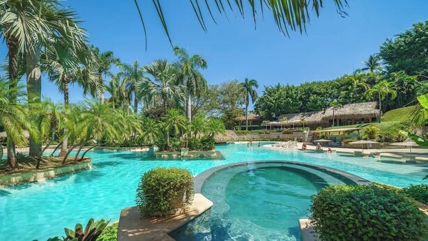 A resort pool surrounded by palm trees and lush greenery. - Matapalo 201 | Steps from Tamarindo Beach (Tamarindo)