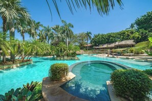 A resort pool surrounded by palm trees and lush greenery. - Matapalo 201 | Steps from Tamarindo Beach (Tamarindo)
