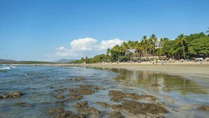 A beach with clear water, rocks, and palm trees. - Matapalo 201 | Steps from Tamarindo Beach (Tamarindo)