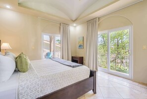 Un dormitorio con cama, cortinas, un cuadro y vistas por una ventana.