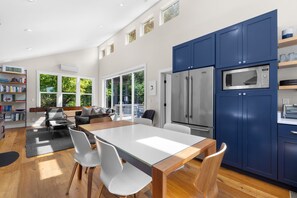 A modern kitchen with blue cabinets, a stainless steel refrigerator, and a built-in microwave.