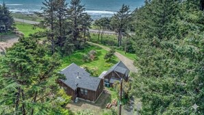 A coastal property with two cabins, surrounded by dense forest and a road leading to the ocean.