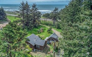 A coastal property with two cabins, surrounded by dense forest and a road leading to the ocean.