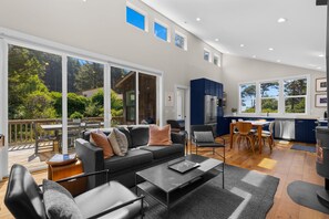 A modern living space with a sofa, chairs, a dining table, and a kitchen area.