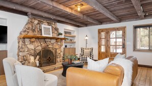 Una sala de estar acogedora con chimenea de piedra, asientos cómodos y un ventanal grande.