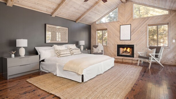 Un dormitorio con una cama grande, una chimenea y un ventilador de techo.