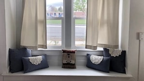 A window seat with two pillows, a small decorative item, and beige curtains. - Cheyenne Cottage- Pet Friendly home, near Northwest College! (Powell)