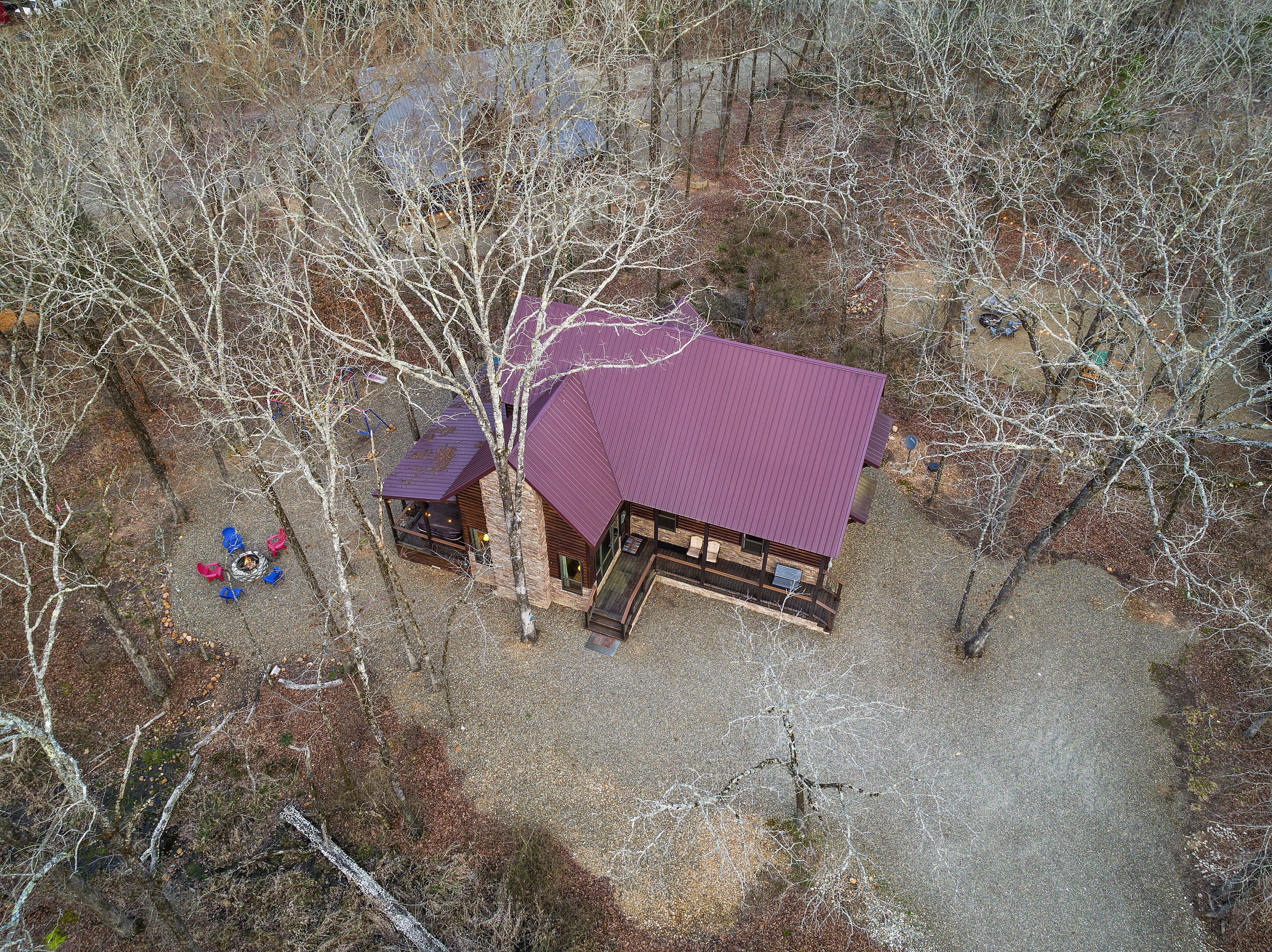 Une cabane avec un toit violet, entourée d’arbres et bordée d’une allée en gravier.