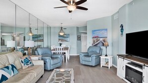 Un salon moderne doté d’un ventilateur de plafond, d’un téléviseur à écran plat et d’une cheminée.