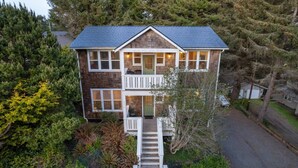 Une maison à deux étages dotée d’un balcon, d’un porche à l’avant et d’une allée menant à l’entrée.