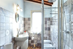 Een bad/douchecombinatie, een regendouche, een haardroger, handdoeken