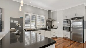 A modern kitchen with a black countertop, stainless steel appliances, and white cabinetry. - Goolwa serenity, Great balcony, Modern, peaceful, water and attractions close by (Goolwa South)