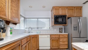 Une cuisine moderne dotée de meubles en bois, d’un lave-vaisselle, d’un four à micro-ondes et d’un réfrigérateur.