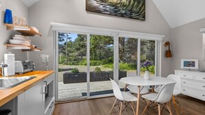 Une cuisine moderne avec un plan de travail en bois, des armoires blanches et un coin repas comprenant des chaises et une table, le tout dans des tons blancs.