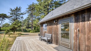 Un bâtiment en bois doté d’une terrasse, d’un banc et d’une porte.