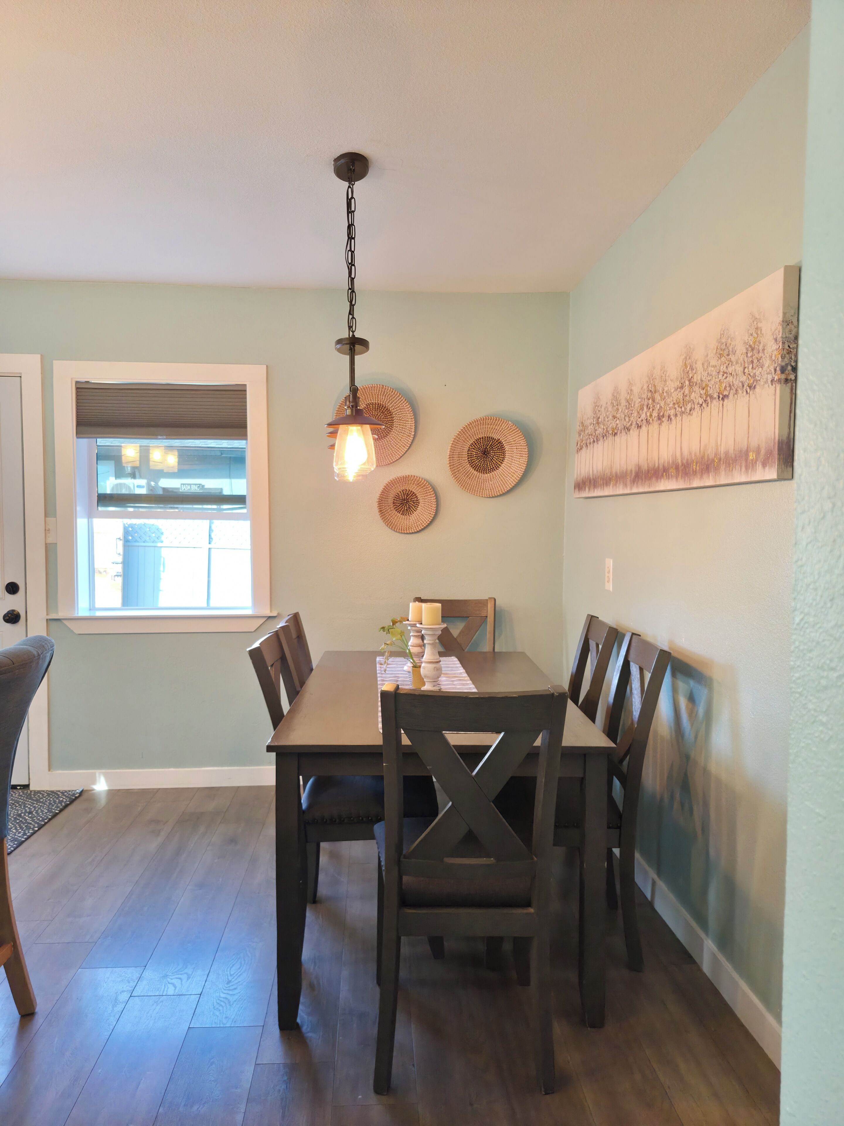 Un espace repas comprenant une table, des chaises, un luminaire suspendu et des éléments décoratifs sur les murs.